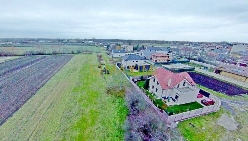 PREDAJ - Stavebný pozemok v meste Stupava - Pohľad na pozemky - bývanie v Stupave s rozmanitým terénom a susednými domami.