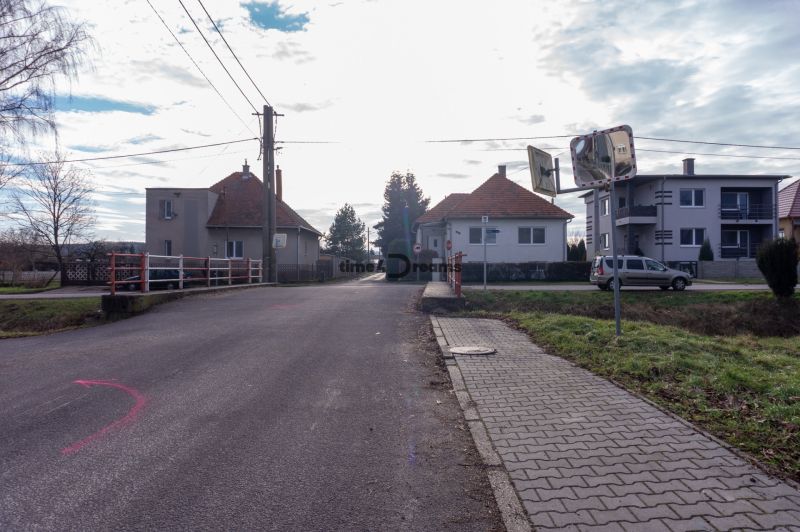 NA PREDAJ pozemky na výstavbu - Pohľad na ulicu so staršími domami, chodníkom a dopravným značením na ulici Športová ul. oproti pozemkom - bývaniu.