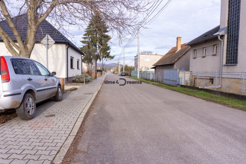 NA PREDAJ pozemky na výstavbu - Ulica s rodinnými domami na Športovej ul. a parkované auto, ideálne pre Pozemky - bývanie.