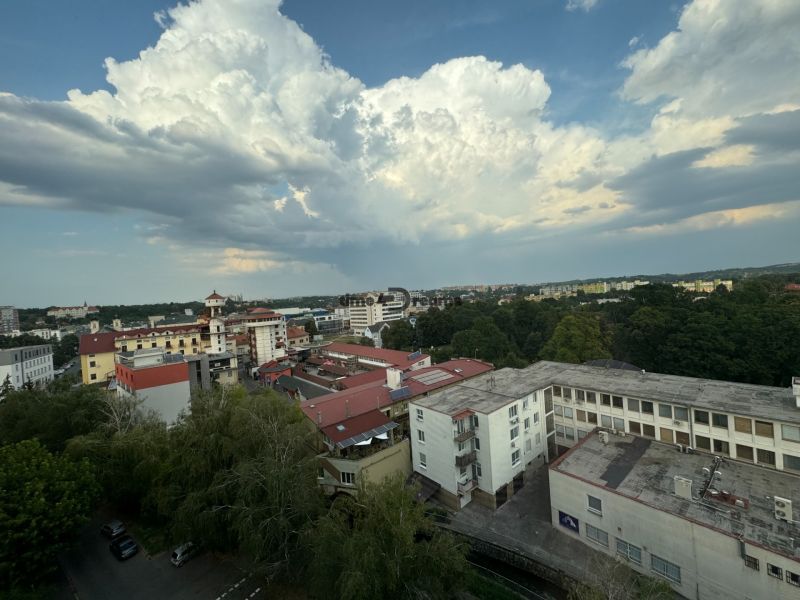 Na predaj: CENTRUM: 3 izb.byt + ŠATNIK + PIVNICA - Panoráma Levic s výhľadom na budovy a oblačnú oblohu v pozadí.