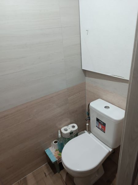 Na prenájom  veľkometrážny 3 izbový byt Nová Baňa - Kúpeľňa v 3-izbovom byte s bielym WC a podlahou s dreveným dekorom.