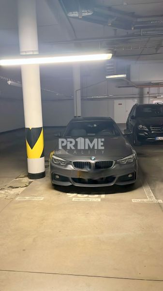 Garážove státie, Manhattan, Račianska ulica - Auto zaparkované v garáži, betonová podlaha, stĺpy s označením, dobré osvetlenie.