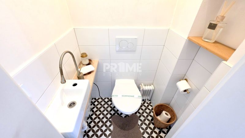 ŠTÝLOVÝ 2i BYT, REKONŠTRUKCIA, BALKÓN, KLÍMA, Murgašová ulica - Toaleta s bielymi obkladmi a vzorovanou podlahou v 2-izbovom byte.