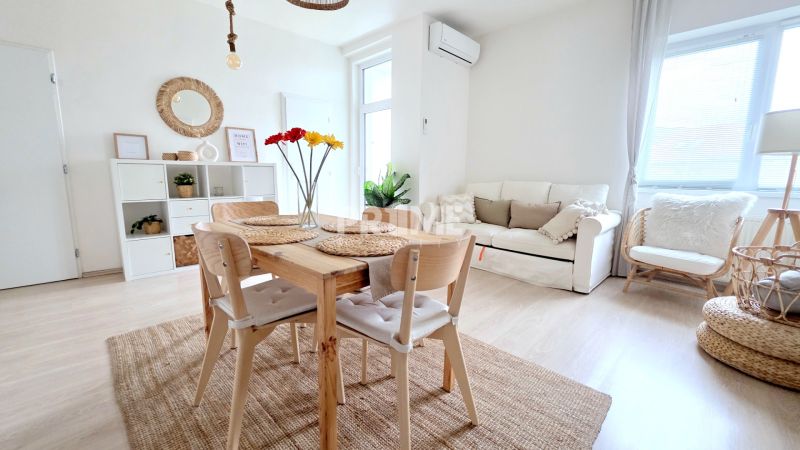 ŠTÝLOVÝ 2i BYT, REKONŠTRUKCIA, BALKÓN, KLÍMA, Murgašová ulica - Svetlý obývací priestor v 2-izbovom byte s jednoduchým dreveným nábytkom a dekoráciami.