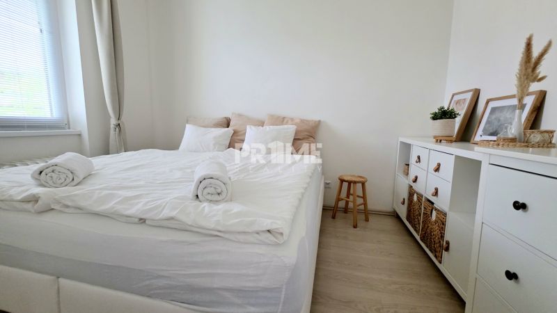 ŠTÝLOVÝ 2i BYT, REKONŠTRUKCIA, BALKÓN, KLÍMA, Murgašová ulica - Svetlá spálňa s posteľou a komodou, podlaha s dreveným dekorom, 2-izbový byt.