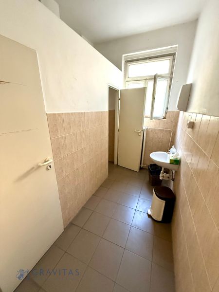 Na predaj – kancelárske priestory v centre  - Toaleta v kanceláriách s oknom a umývadlom, svetlé obklady na stenách.