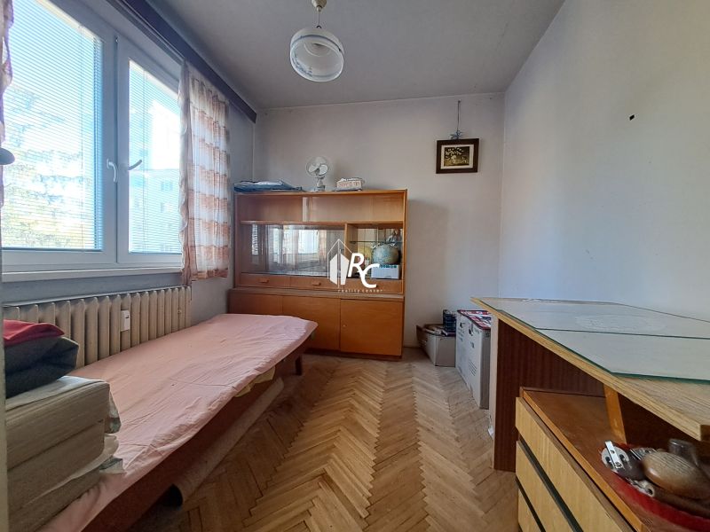 Centrum Martina slnečný 3-izbový byt s balkónom a potenciálom - Malá izba so sedačkou a vitrínou v 3-izbovom byte, podlaha s dreveným dekorom.