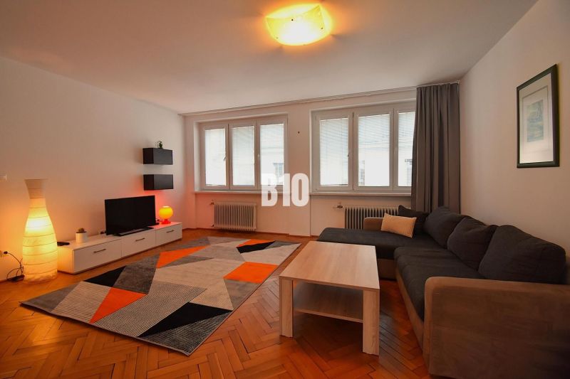 NA PRENÁJOM Priestranný 3 izbovy byt Žilina  - centrum mesta , FOR REN - 3-izbový byt s podlahou s dreveným dekorom, šedou sedačkou a pestrofarebným kobercom.