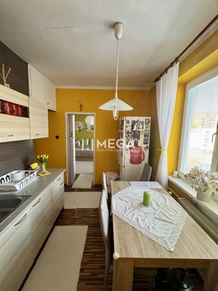 PREDANÉ- 2 izbový byt s balkónom blízko centra mesta Humenné - Kuchyňa v 2-izbovom byte s jedálenským stolom a podlahou s dreveným dekorom.