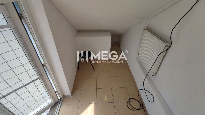 PRENÁJOM obchodných priestorov v centre mesta Humenné-3m2 - Úzky priestor s radiátorom, stoličkou a dlažbou v obchodných priestoroch.