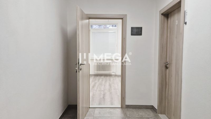 PRENÁJOM komerčného priestoru (26 m2) blízko centra Humenné - Otvorené dvere vedú do miestnosti s podlahou s dreveným dekorom v obchodných priestoroch.