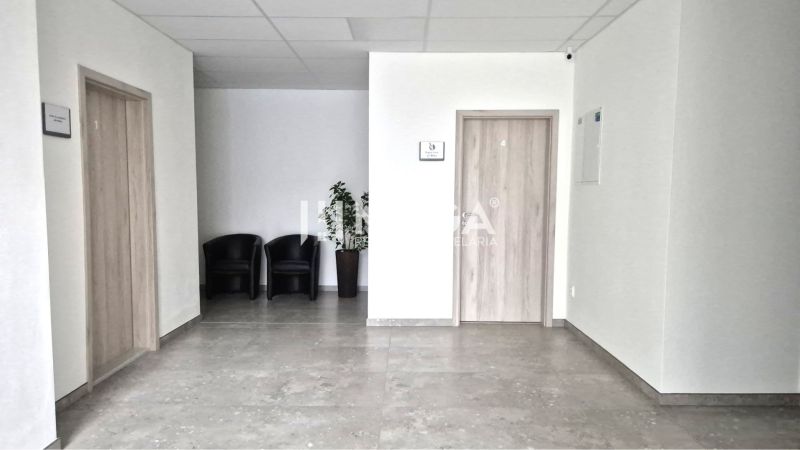 PRENÁJOM komerčného priestoru (26 m2) blízko centra Humenné - Interiér obchodných priestorov s kreslami, dlažbou a dverami s dreveným dekorom.