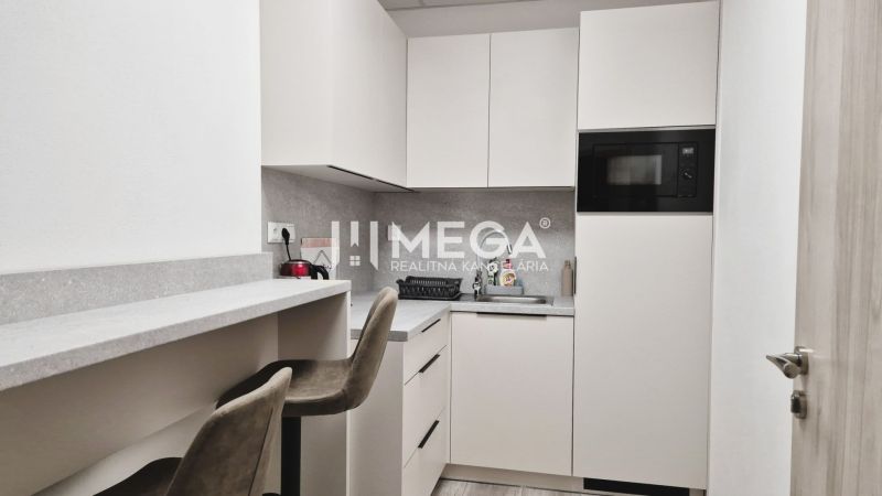PRENÁJOM komerčného priestoru (26 m2) blízko centra Humenné - Kuchyňa v obchodných priestoroch s minimalistickými bielymi skrinkami a pultom na sedenie.