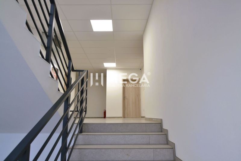 PRENÁJOM komerčného priestoru (26 m2) blízko centra Humenné - Schodisko v obchodných priestoroch s kovovým zábradlím a svetlou stenou.