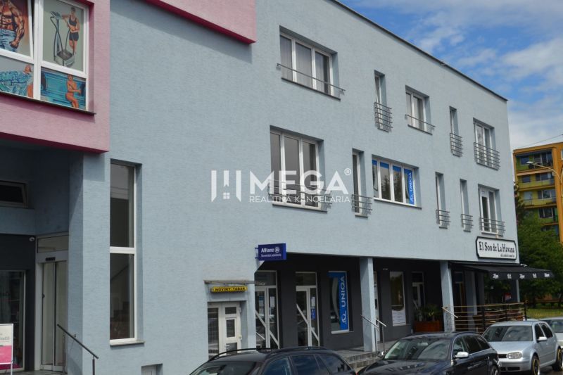 PRENÁJOM obchodného priestoru v centre Humenného (74 m2) - Obchodné priestory na ulici Osloboditeľov v Humennom s farebnou fasádou a autami v popredí.