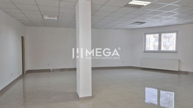 PRENÁJOM obchodného priestoru v centre Humenného (74 m2) - Priestranné obchodné priestory s dlažbou a bielymi stenami, svetlo preniká cez okno.
