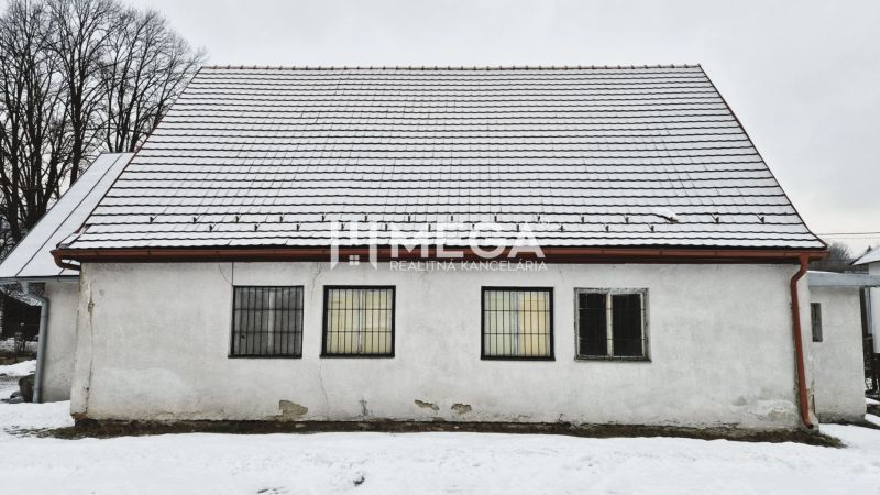 Predaj budovy v obci Zboj - Snehom pokryté obchodné priestory v meste Zboj s jednoduchou fasádou a mriežkami na oknách.