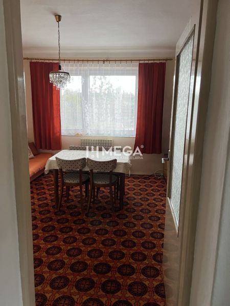 Znížena cena domu na Jesenského ulici v Snine - Interiér rodinného domu s kobercom v červenom dekore, jedálenský stôl a luster.