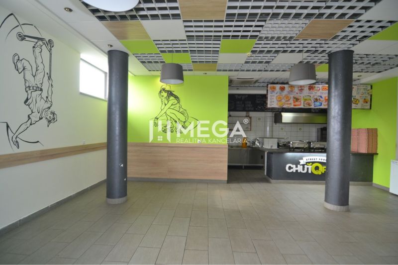 NA PRENÁJOM TOP GASTRO PRIESTOR NA PRENÁJOM – BEZ DEPOZITU - Interiér obchodných priestorov s výzdobou na stenách a otvorenou kuchyňou.