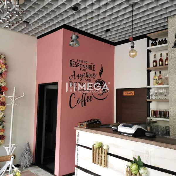 ODSTÚPENIE ZABEHNUTEJ REŠTAURÁCIE Bistro Dominika–VRANOV N/T - Stena s nápisom v gastro priestoroch, podlaha s dreveným dekorom, kvety, regály.
