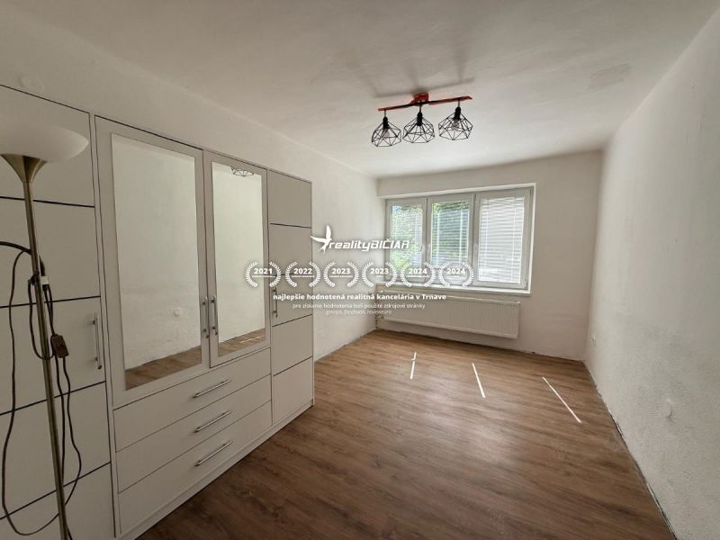V exkluzívnom zastúpení majiteľa ponúkame na predaj rodinný dom - Izba v rodinnom dome s bielymi stenami, šatníkom a podlahou s dreveným dekorom.