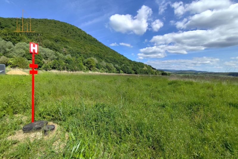 Na predaj pozemky vo Veľkom Šariši - Zelená lúka a kopce pod modrou oblohou blízko Veľkého Šariša. Výrobné priestory v prírode.