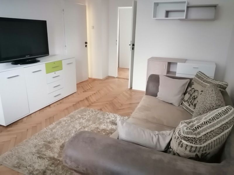 PRENÁJOM: ÚTULNÝ 2 IZBOVÝ BYT S BALKÓNOM, UHLISKO - Obývacia izba v 2-izbovom byte s pohodlnou pohovkou, drevený dekor podlahy a TV.