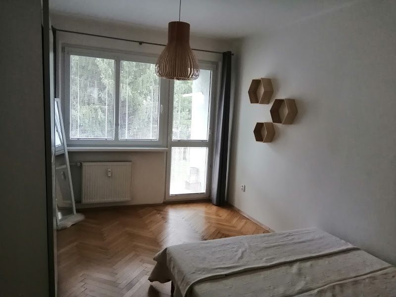 PRENÁJOM: ÚTULNÝ 2 IZBOVÝ BYT S BALKÓNOM, UHLISKO - Spálňa s podlahou s dreveným dekorom a veľkým oknom v 2-izbovom byte.
