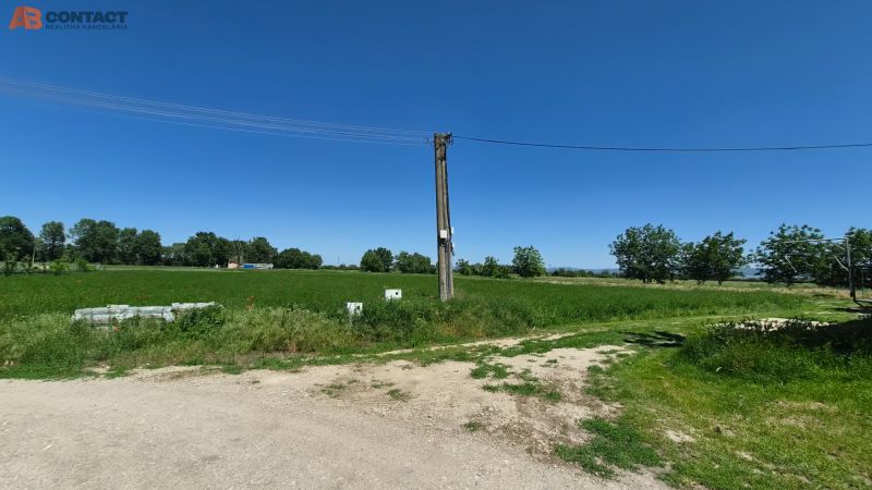 Stavebný pozemok v pokojnej časti obce Veselé - Pozemky - bývanie na Veselé pri Veselom s elektrickým stĺpom uprostred zelenej krajiny.