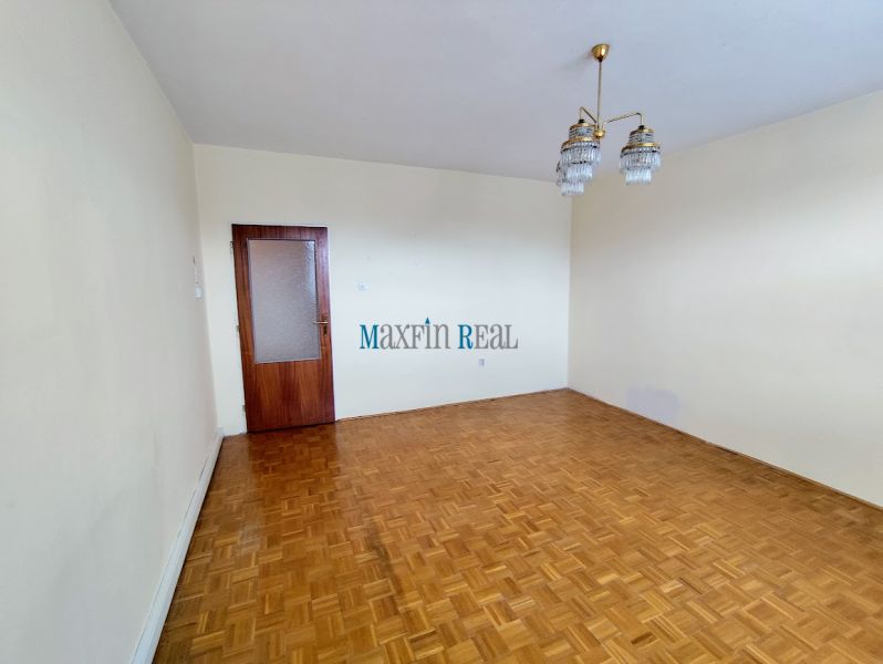 Na predaj priestranný 3-izbový byt s garážou v Nitre – Chrenová - Priestranná izba s podlahou s dreveným dekorom, luster a dverami.