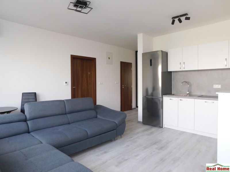 Moderný 2-izbový byt na prenájom-Hviezdoslavov–parkovanie,klimatizácia - Obývačka s kuchyňou v 2-izbovom byte, sivá sedačka, biela kuchynská linka.