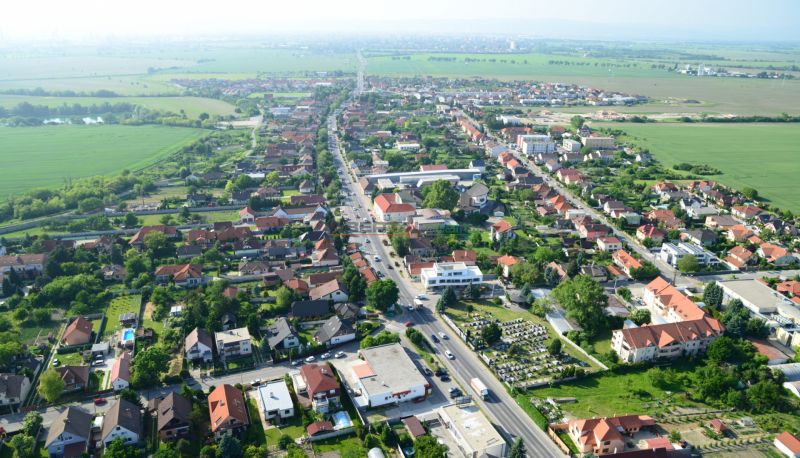 3-izb. byt na prenájom, Rovinka – novostavba, klimatizácia, parkovanie - Letecký pohľad na zástavbu v Rovinke na Broskyňovej ulici a okolitú krajinu.