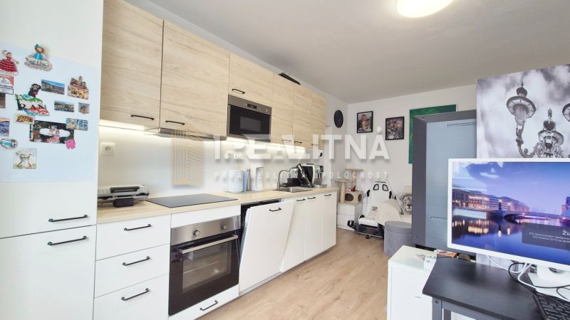 MODERNÝ DVOJIZBOVÝ BYT, 37M2, DÚBRAVKA - Kuchyňa v 2-izbovom byte s bielymi skriňami, podlahou s dreveným dekorom a dekoráciami na stene.
