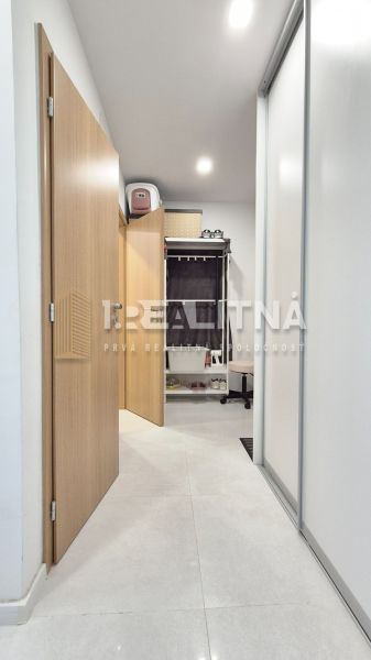 MODERNÝ DVOJIZBOVÝ BYT, 37M2, DÚBRAVKA - Chodba v 2-izbovom byte s dlažbou, vstavanými skriňami a otvorenými dverami vedúcimi k úložnemu priestoru.