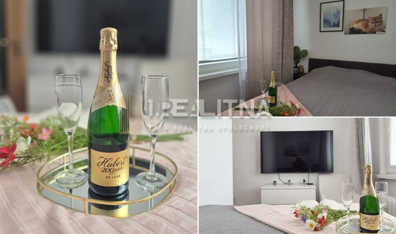 MODERNÝ DVOJIZBOVÝ BYT, 37M2, DÚBRAVKA - 2-izbový byt s posteľou, šampanským, dvoma pohármi a TV na stene.