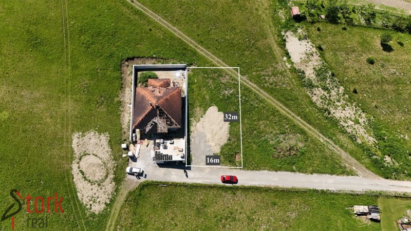 Iba 10km od Žiliny - STAVEBNÝ POZEMOK - Lietavská Svinná - Lietavská Svinná-Babkov: Parcelka pre bývanie, zelená lúka s rozostavaným domom a vozidlami.