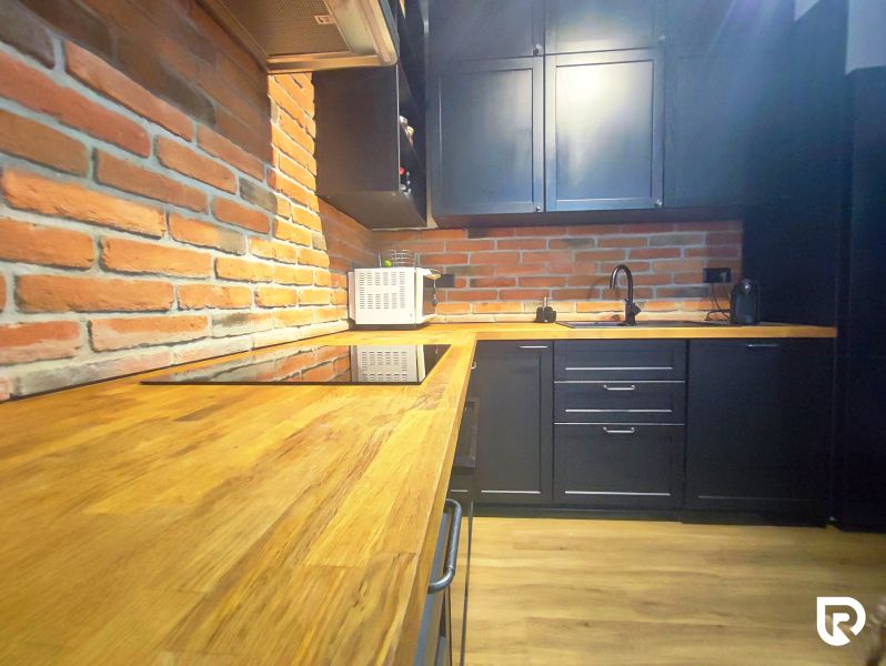 | Srdce Mesta | 2 Izb. byt | ORBIS |  70 m2 - Kuchyňa v 2-izbovom byte s tehlovou stenou a podlahou s dreveným dekorom.