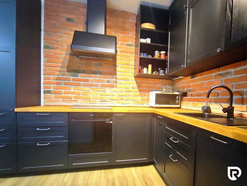 | Srdce Mesta | 2 Izb. byt | ORBIS |  70 m2 - Kuchyňa v 2-izbovom byte s tehlovou stenou a podlahou s dreveným dekorom.