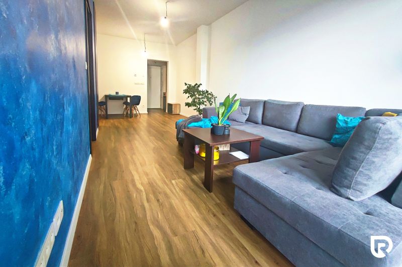 | Srdce Mesta | 2 Izb. byt | ORBIS |  70 m2 - Obývacia izba s podlahou s dreveným dekorom a modrou stenou v 2-izbovom byte.