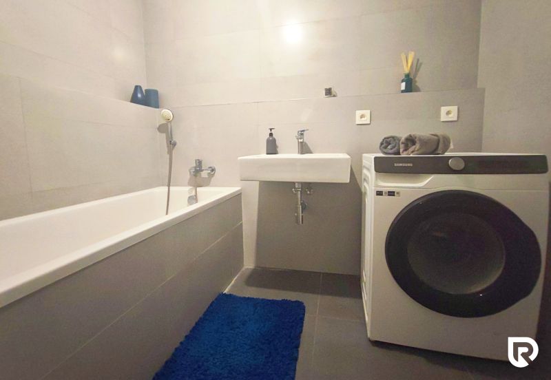 | Srdce Mesta | 2 Izb. byt | ORBIS |  70 m2 - Kúpeľňa v 2-izbovom byte s vaňou, umývadlom a práčkou na podlahe s dlažbou.