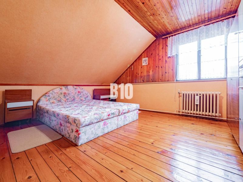 Bývanie alebo podnikanie priamo pod HRADOM? - Podkrovná spálňa v rodinnom dome s kvetinovým matracom a podlahou s dreveným dekorom.