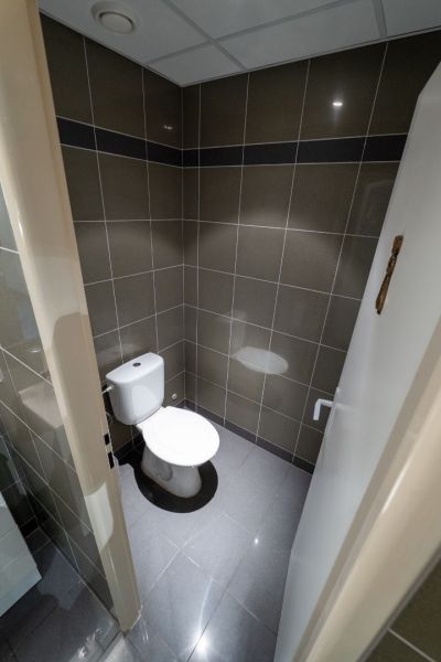 Meštiansky dom v centre Banskej Bystrice a parkovaním pre 24 áut D135Z - Kúpeľňa s toaletou, dlaždicami a sivou podlahou s keramickým dekorom.