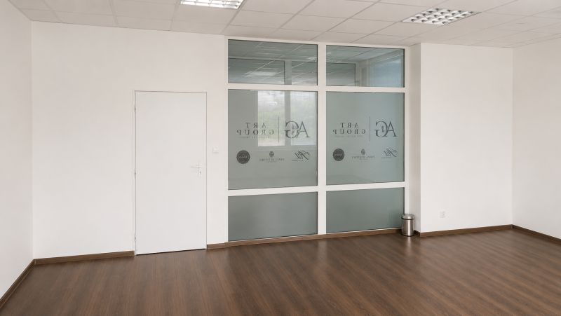 Prenájom obchodných, kancelárskych  priestorov – Banská Bystrica - Prázdne obchodné priestory s podlahou s dreveným dekorom a sklenenými priečkami.