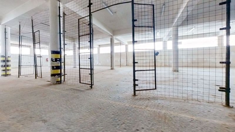Na prenájom skladové priestory - Zvolen NO023ZL - Oplotený interiér skladu a haly s otvorenými bránami a svetlými stenami.