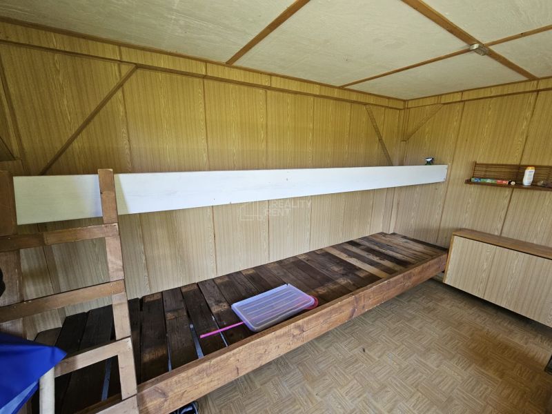 PREDAJ: Záhradná chatka s pozemkom Žilina - Budatín (MO) - Interiér chaty s palandou, podlahou s dreveným dekorom a drevenou stenou.