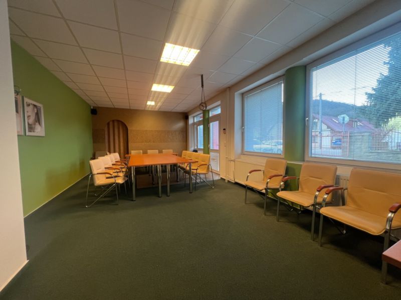 Prenájom skladové priestory s kanceláriami od 200 m² – Banská Bystrica - Miestnosť s konferenčným stolom a stoličkami, veľké okná, podlaha s dreveným dekorom.