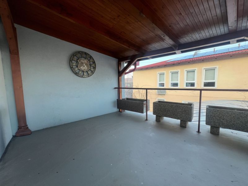 Prenájom skladové priestory s kanceláriami od 200 m² – Banská Bystrica - Krytá terasa s hodinami a kvetináčmi vo výrobných priestoroch.