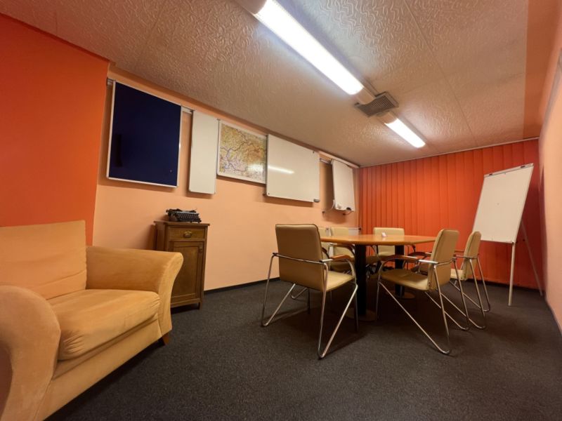 Sklad + kancelárie 1349 m² logistický objekt s rampami -Banská Bystria - Konferenčná miestnosť s oranžovými stenami, stoličkami, bielou tabuľou a flipchartom.