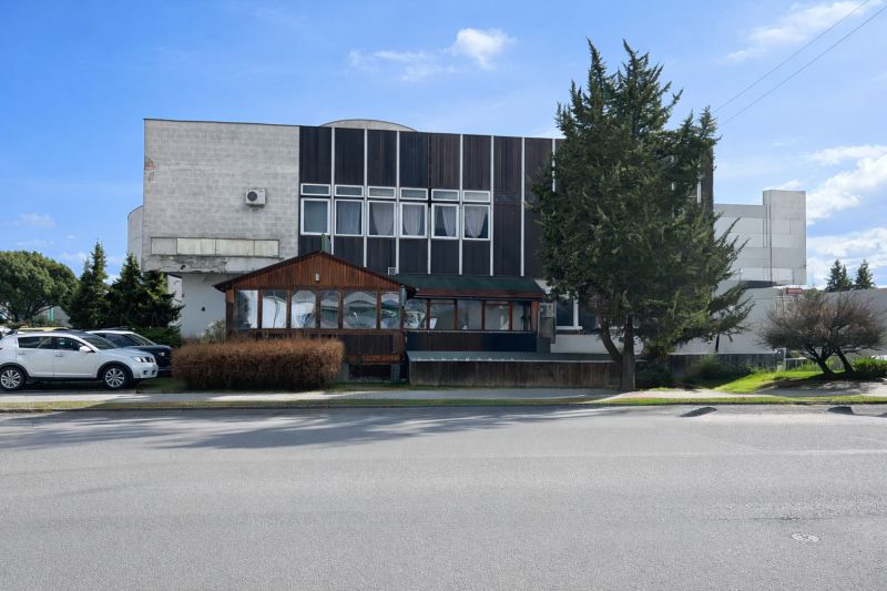 Komerčné priestory pri hlavnej ceste s parkoviskom -Žiar nad Hronom - Exteriér gastro priestorov v Žiari nad Hronom, obklopený stromami a zaparkovanými autami.
