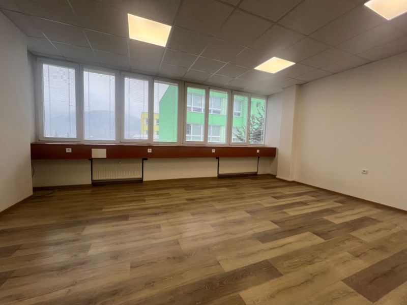 Prenájom kancelárske priestory 27 m² -Banská Bystrica, Zvolenská cesta - Prázdna kancelária s podlahou s dreveným dekorom a veľkými oknami.